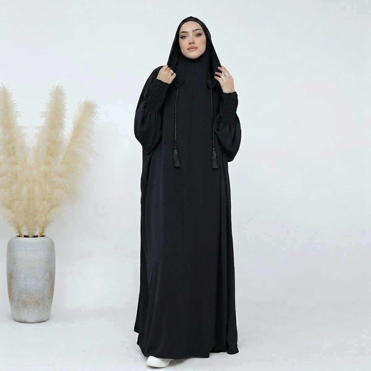 Hooded prayer abaya jilbab in black, full-length front view, smocked sleeves with tassel drawstrings